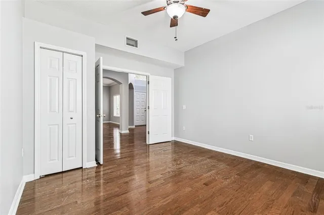 an empty room with wooden floor & windows