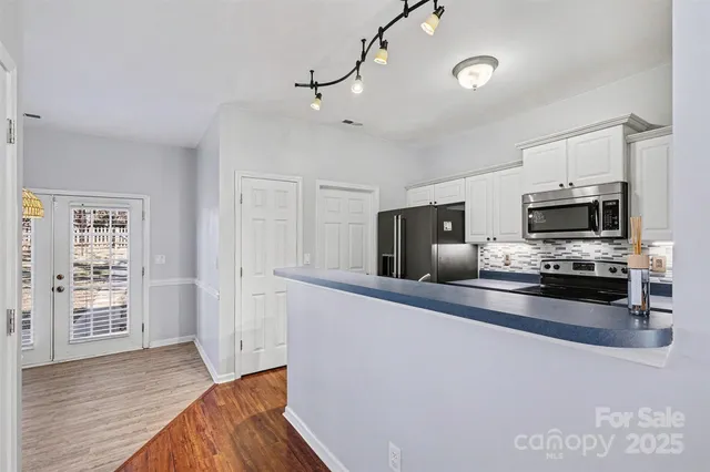 a kitchen with stainless steel appliances a sink a microwave a refrigerator and cabinets