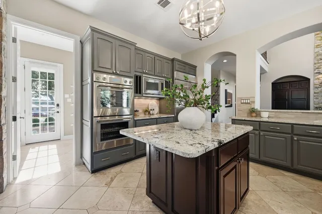 a kitchen with stainless steel appliances granite countertop a sink dishwasher stove and white cabinets with wooden floor