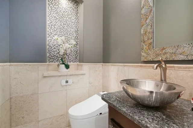 a bathroom with a granite countertop toilet sink and mirror