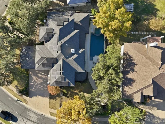 an aerial view of a house with a yard and large trees
