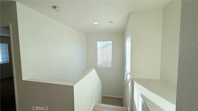 a view of a hallway with wooden floor and a bathroom