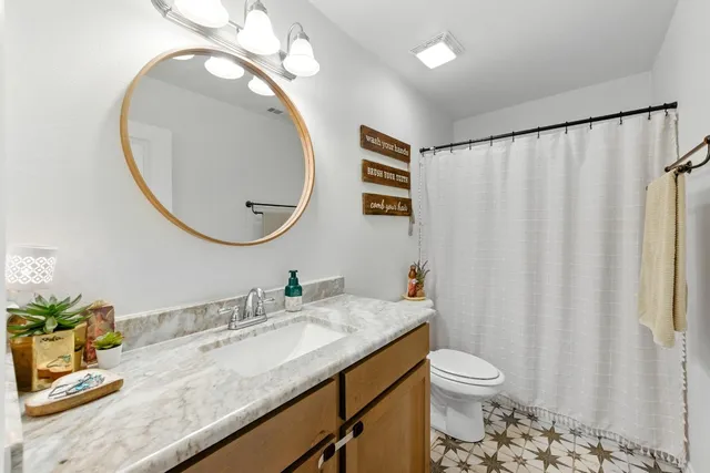 a bathroom with a granite countertop sink a mirror and a toilet