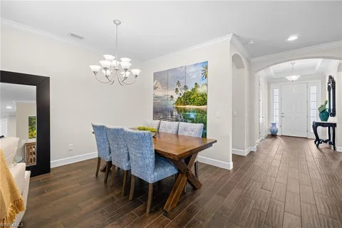 a dining room with furniture wooden floor a chandelier and a mirror