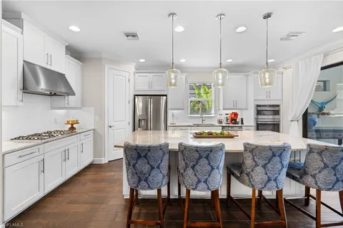 a kitchen with stainless steel appliances kitchen island granite countertop a stove a sink a oven a dining table and chairs