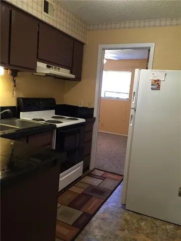 a kitchen with stainless steel appliances granite countertop a refrigerator a stove and a sink with wooden floor