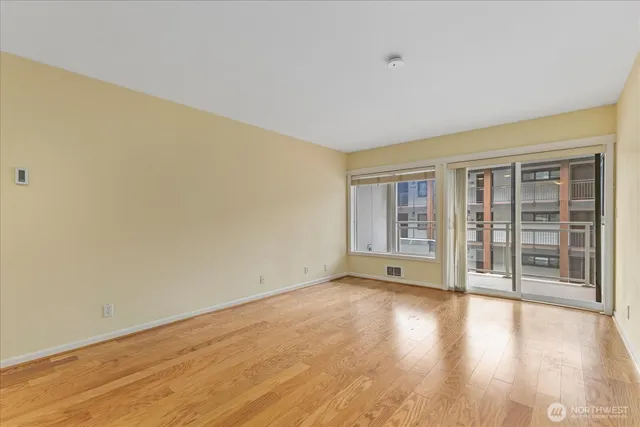 a view of an empty room with wooden floor and a window