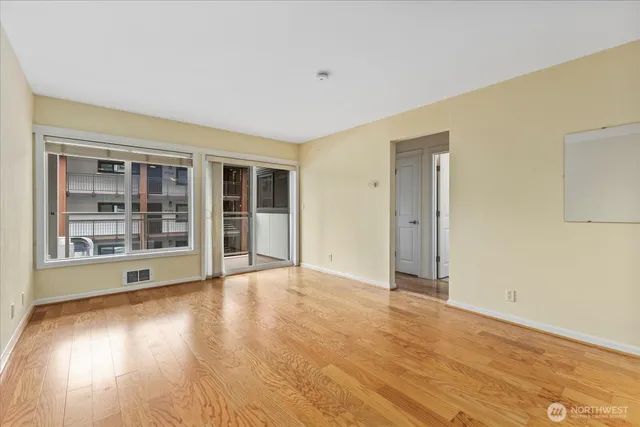 a view of an empty room with wooden floor and a window