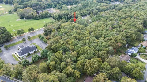 an aerial view of residential house with outdoor space and trees all around