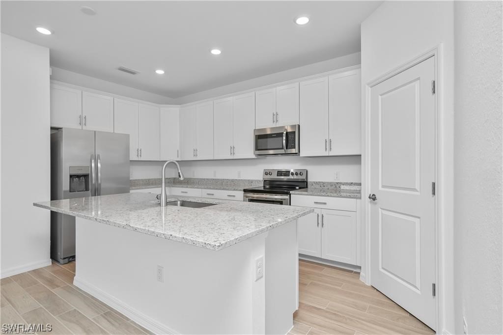 1395 Birdie Drive Naples, FL 34120 - Photo 6 of 17 a kitchen with stainless steel appliances granite countertop a refrigerator sink and white cabinets