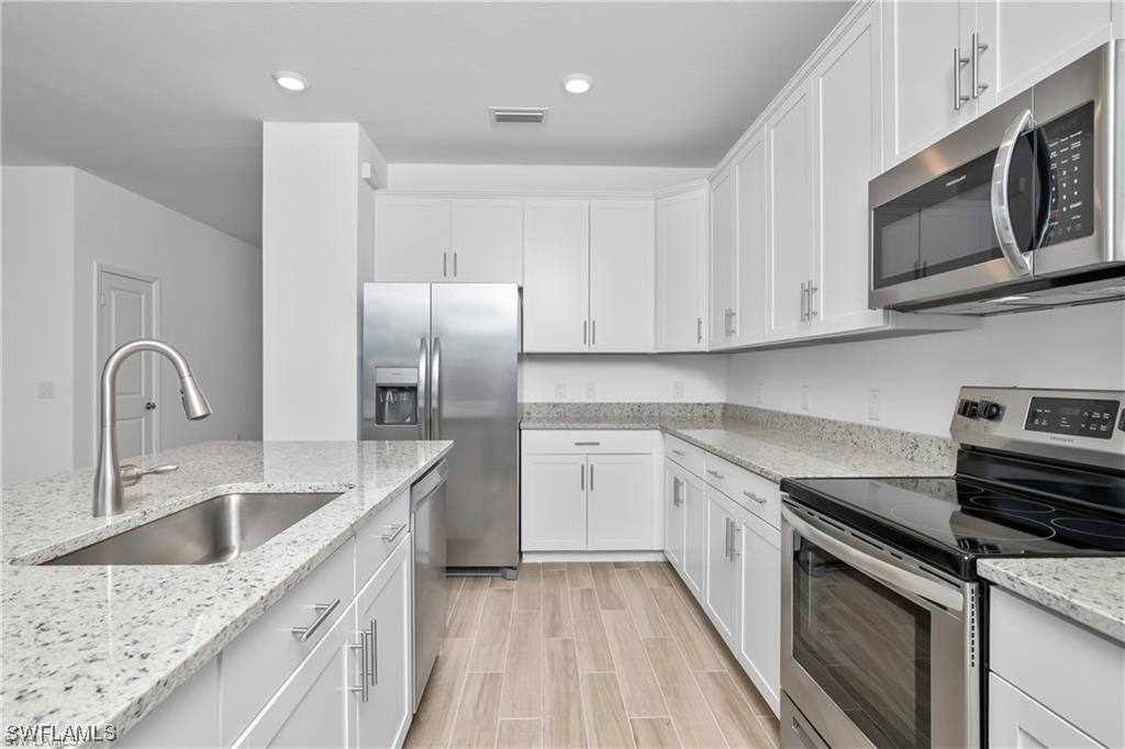 1395 Birdie Drive Naples, FL 34120 - Photo 7 of 17 a kitchen with granite countertop white cabinets and stainless steel appliances