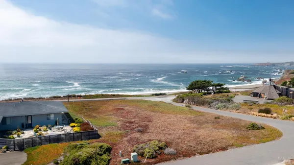 an aerial view of ocean and residential houses with outdoor space