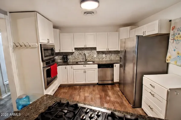 a kitchen with granite countertop a stove top oven microwave and cabinets