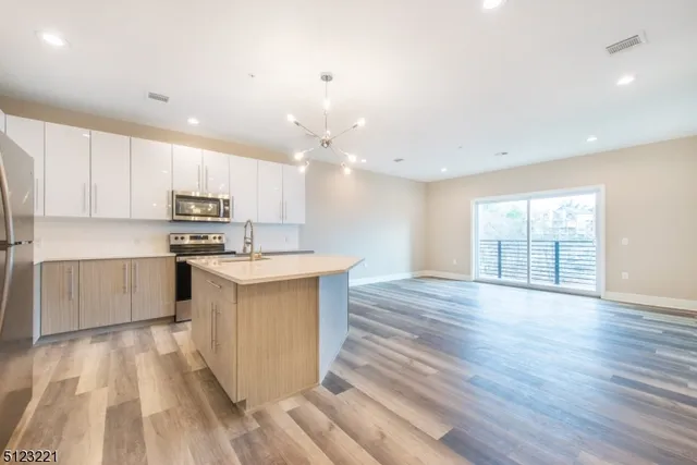 a kitchen with stainless steel appliances a stove top oven a sink cabinets and wooden floor