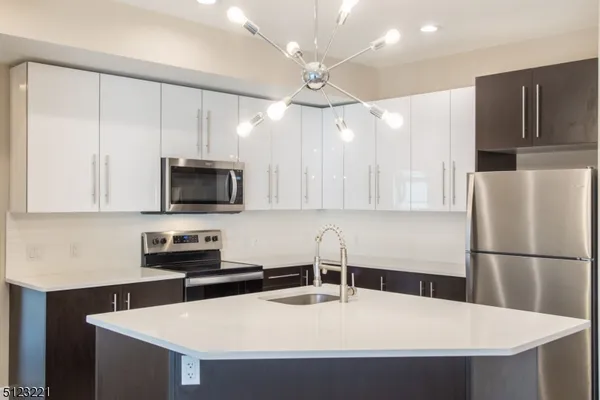 a kitchen with stainless steel appliances granite countertop a sink a microwave a refrigerator and white cabinets