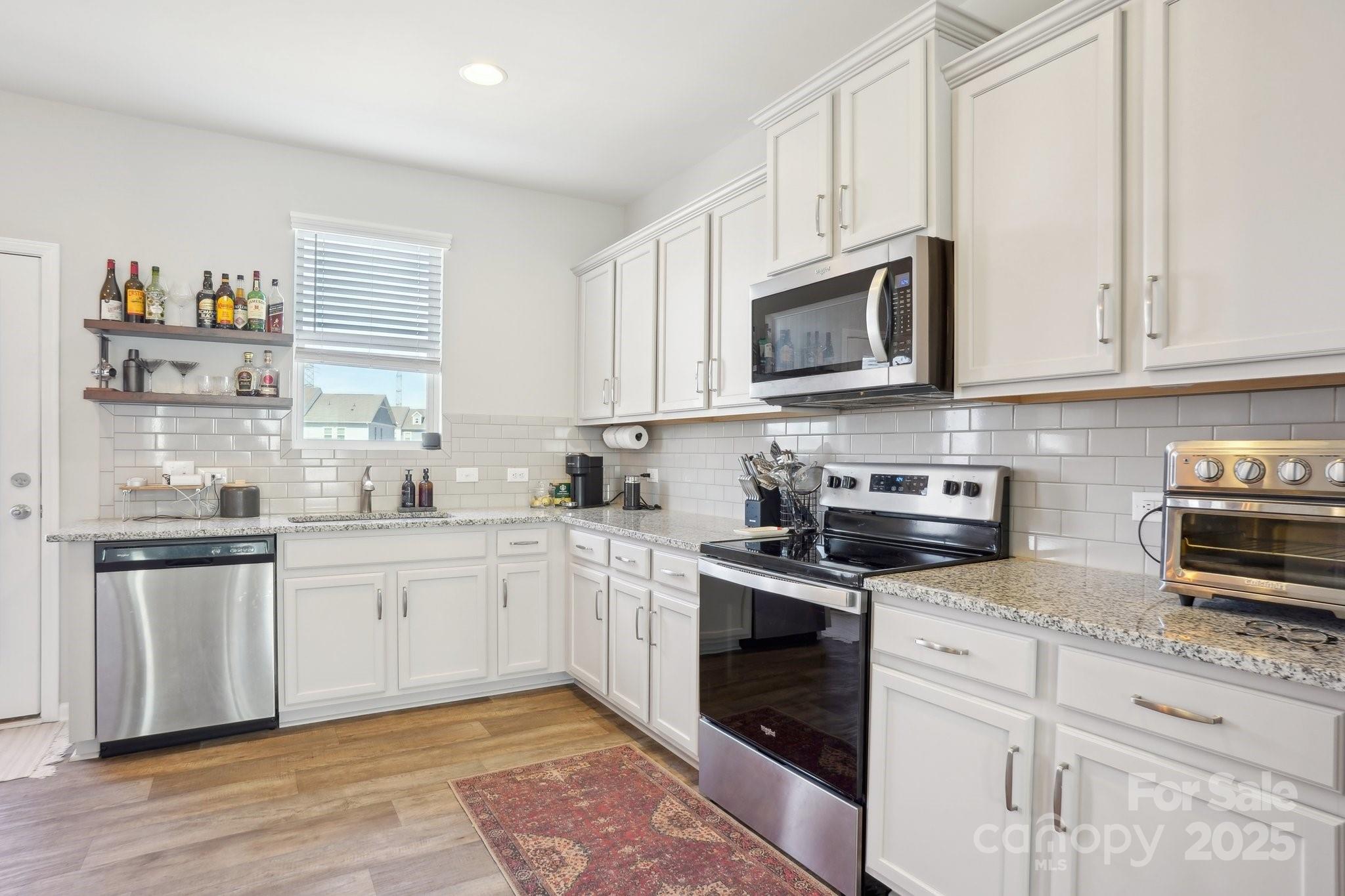 12461 Bryton Ridge Parkway Huntersville, NC 28078 - Photo 10 of 33 a kitchen with stainless steel appliances granite countertop a stove a sink and a microwave