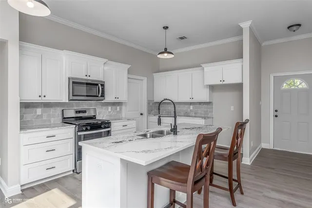 a kitchen with stainless steel appliances kitchen island granite countertop a table chairs microwave and cabinets