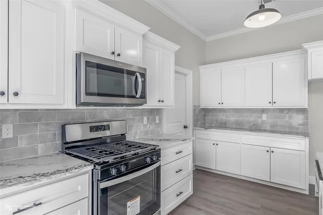 a kitchen with granite countertop white cabinets and stainless steel appliances