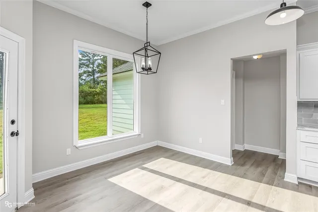 a view of an empty room with a window and wooden floor