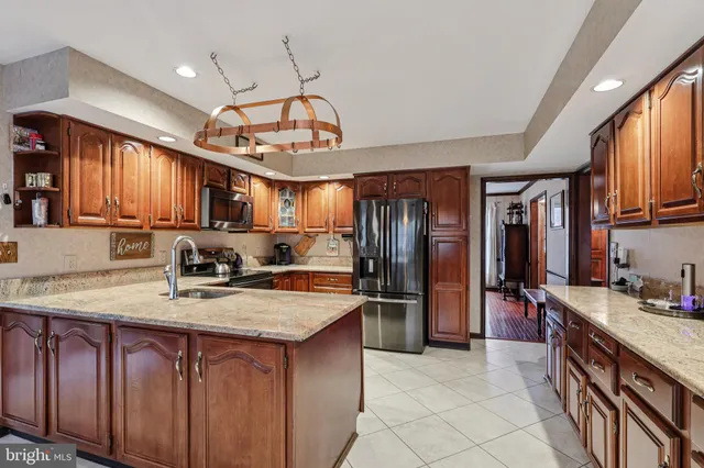 a kitchen with kitchen island granite countertop a sink appliances cabinets and a counter top space