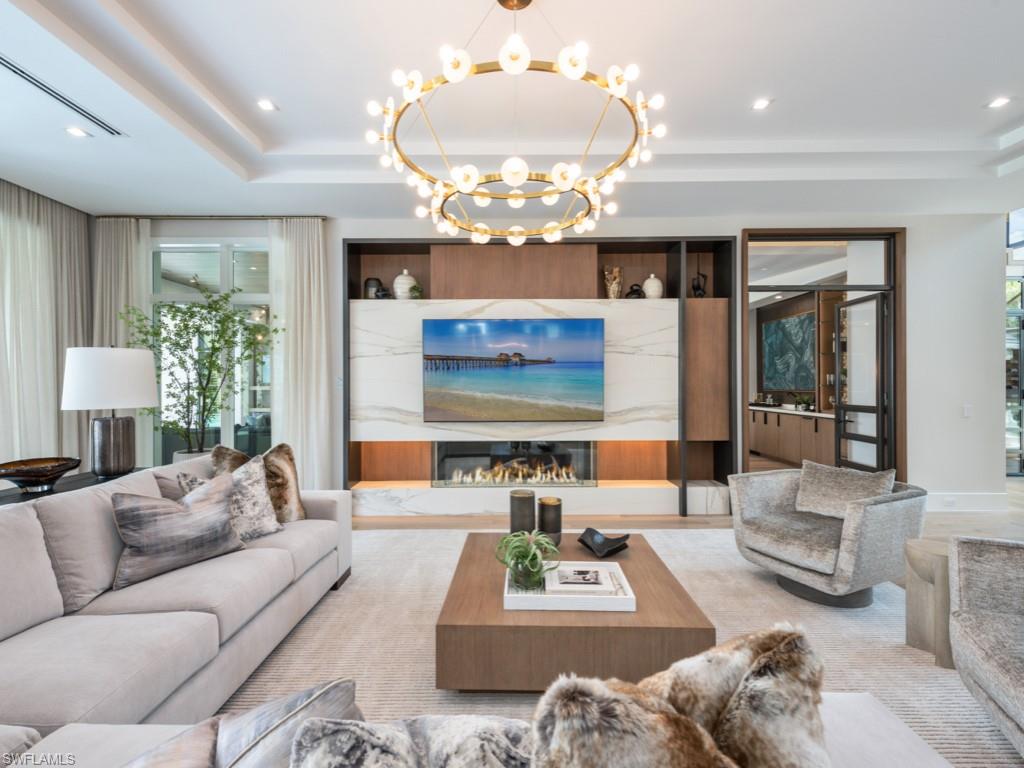 349 Colony Drive Naples, FL 34108 - Photo 13 of 48 Living room featuring a chandelier and a tray ceiling
