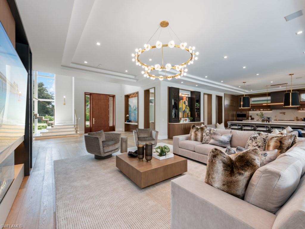349 Colony Drive Naples, FL 34108 - Photo 14 of 48 Living room featuring light wood-type flooring, a raised ceiling, and a notable chandelier