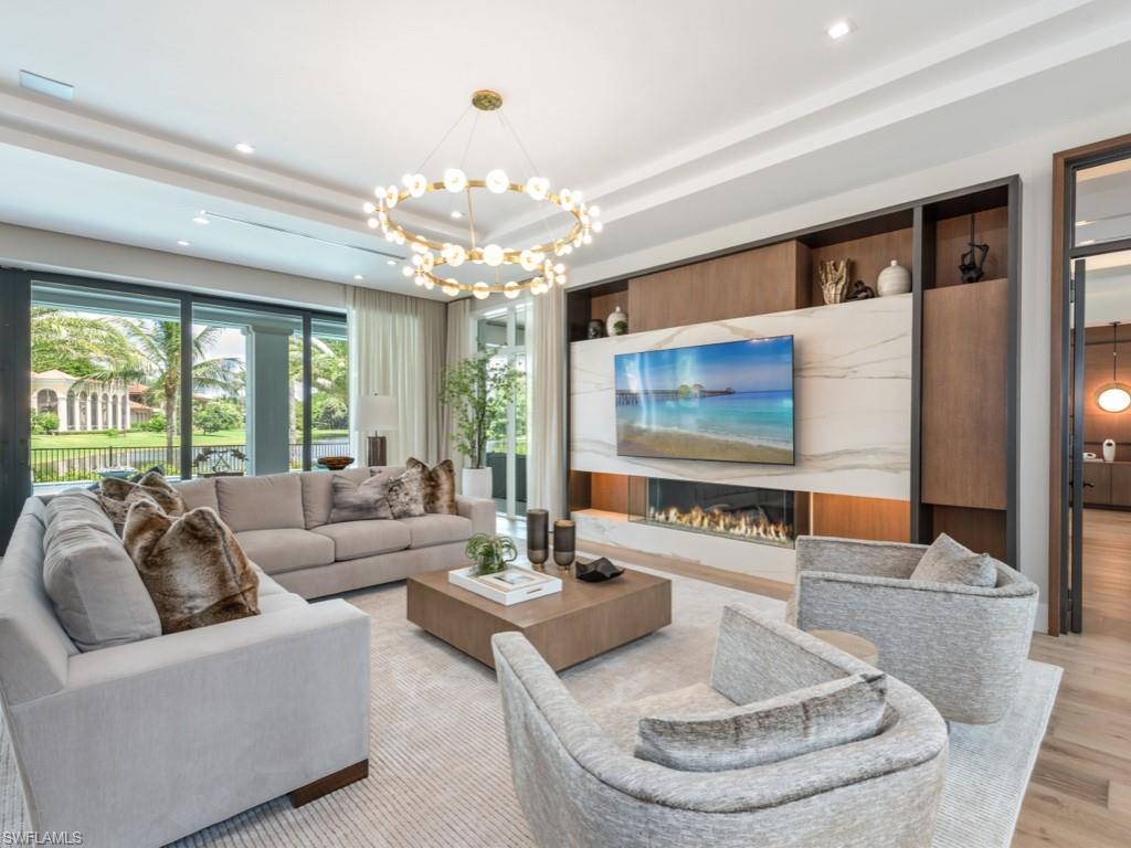 349 Colony Drive Naples, FL 34108 - Photo 15 of 48 Living room with a raised ceiling, a notable chandelier, and light hardwood / wood-style floors