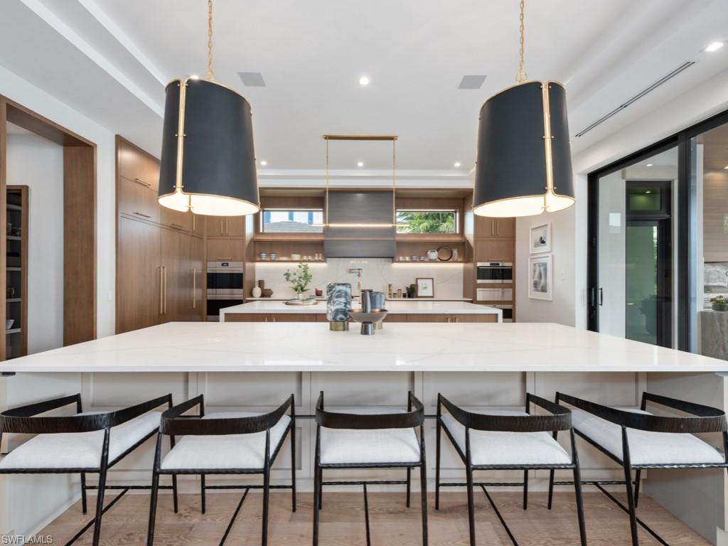 349 Colony Drive Naples, FL 34108 - Photo 20 of 48 Kitchen featuring a breakfast bar area, range hood, a large island, and tasteful backsplash