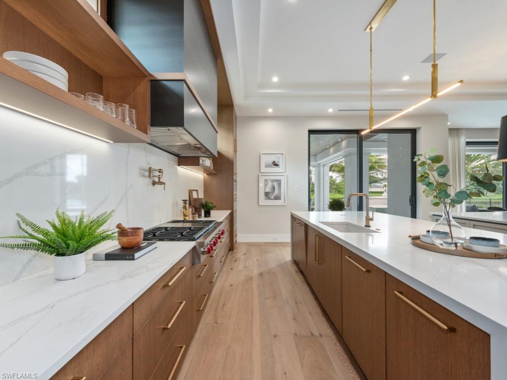 349 Colony Drive Naples, FL 34108 - Photo 21 of 48 Kitchen featuring stainless steel gas stovetop, hanging light fixtures, light hardwood / wood-style flooring, sink, and wall chimney exhaust hood