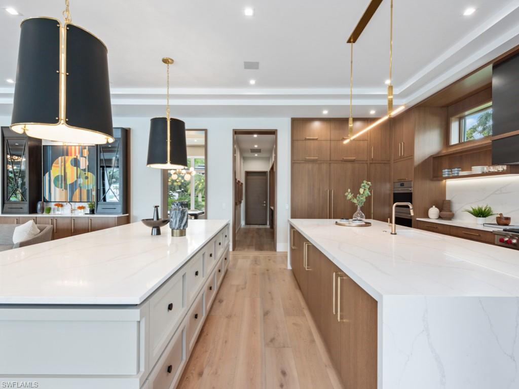 349 Colony Drive Naples, FL 34108 - Photo 22 of 48 Kitchen with a large island with sink, hanging light fixtures, light stone counters, and white cabinets