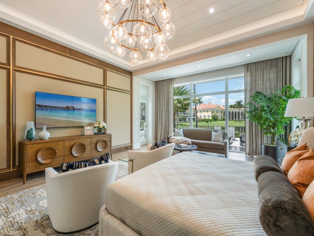 349 Colony Drive Naples, FL 34108 - Photo 24 of 48 Bedroom with light wood-type flooring, a raised ceiling, and an inviting chandelier