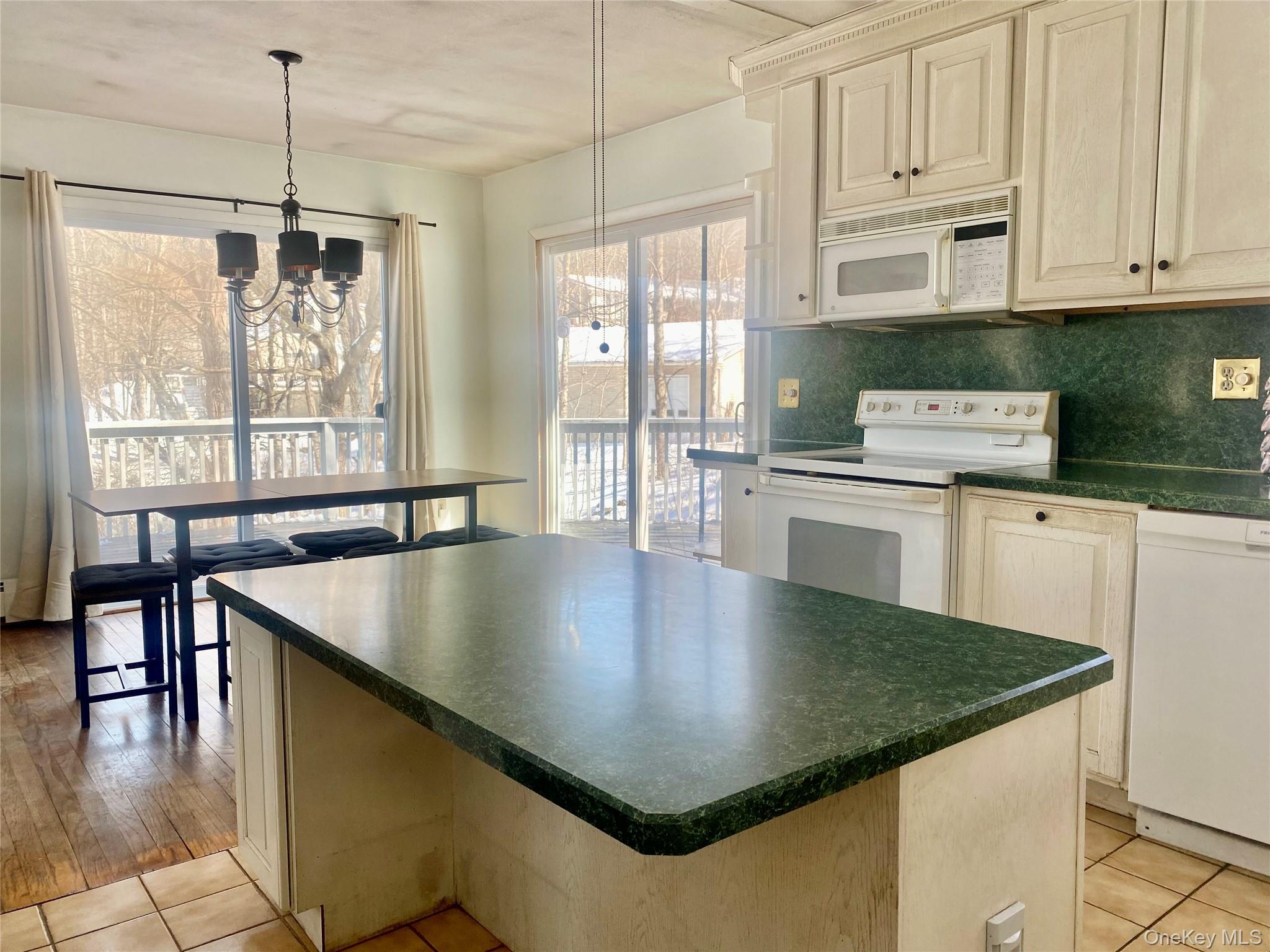 182 Downing Road Pleasant Valley, NY 12569 - Photo 2 of 29 Kitchen featuring white appliances, dark countertops, tasteful backsplash, suspended lighting, and healthy amount of natural light