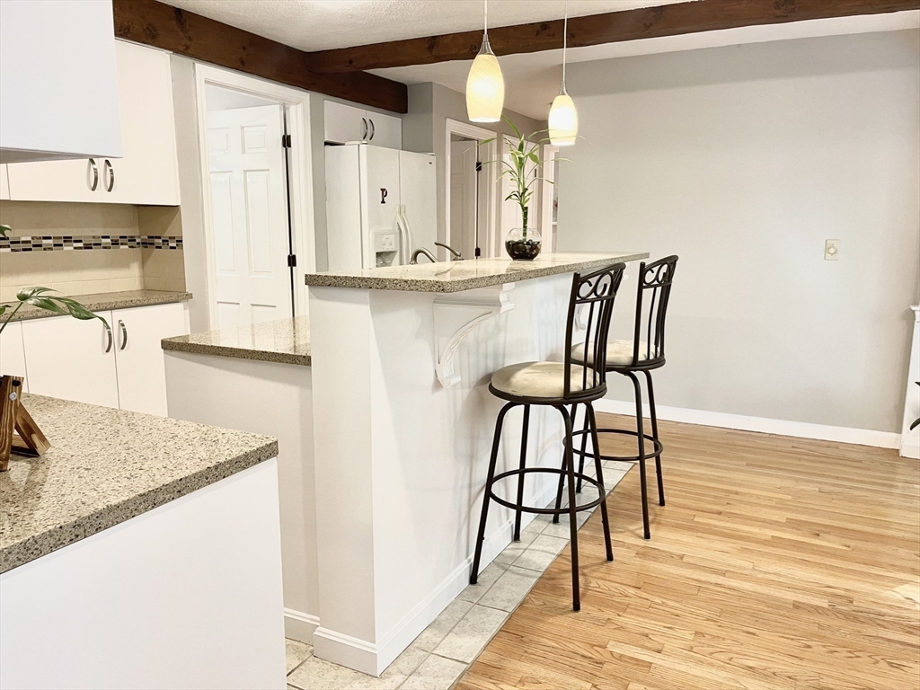 42 Jackson Drive Acton, MA 01720 - Photo 15 of 39 a kitchen with stainless steel appliances kitchen island granite countertop a table chairs in it and wooden floors