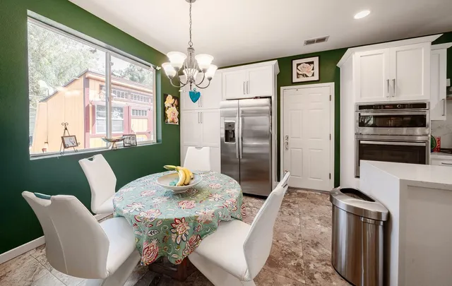a kitchen with stainless steel appliances granite countertop a dining table chairs and refrigerator