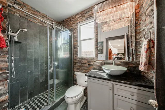 a bathroom with a granite countertop sink a toilet a mirror and shower