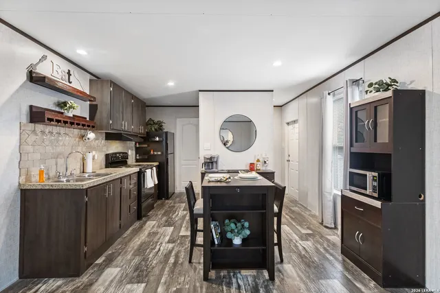 a kitchen with granite countertop a refrigerator stove top oven and sink