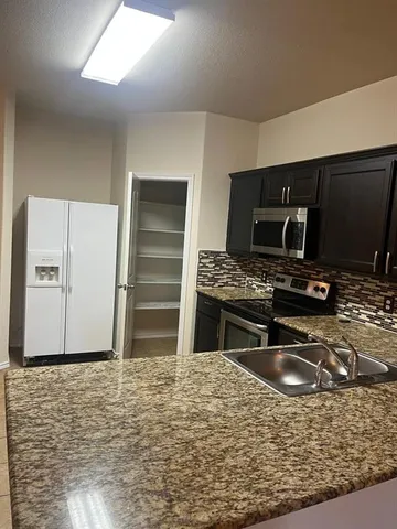 a kitchen with stainless steel appliances granite countertop a sink stove and refrigerator