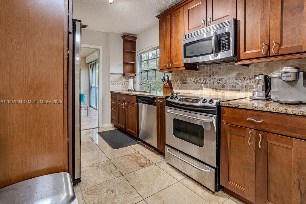 6500 Via Regina, Unit 8 Boca Raton, FL 33433 - Photo 6 of 31 a kitchen with stainless steel appliances granite countertop a stove a sink and a microwave
