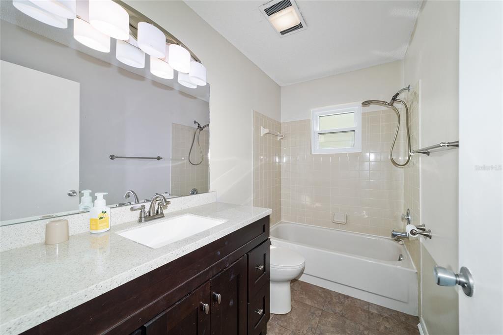 8877 Southwest 96th Street, Unit D Ocala, FL 34481 - Photo 36 of 51 a bathroom with a granite countertop sink mirror toilet and bathtub