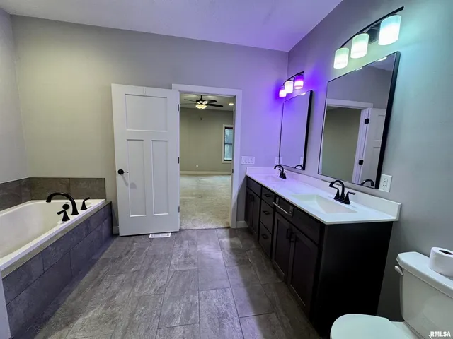 a bathroom with a double vanity sink a mirror a toilet and bathtub