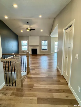 a view of a hallway with wooden floor and a kitchen