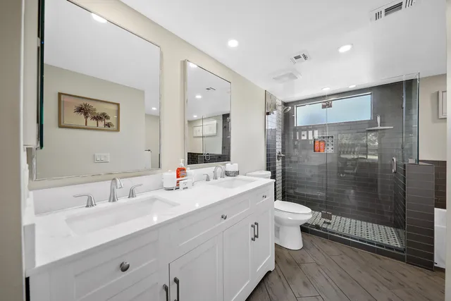 a bathroom with a double vanity sink toilet and shower