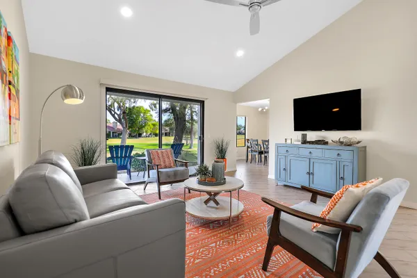 a living room with furniture a flat screen tv and a floor to ceiling window