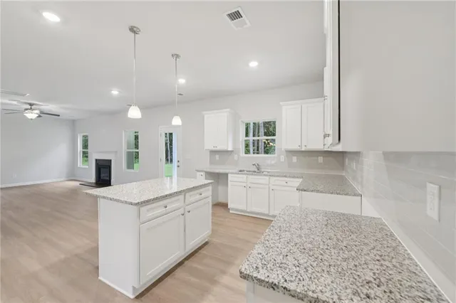 a large white kitchen with a white countertops a sink and a stove with wooden floor
