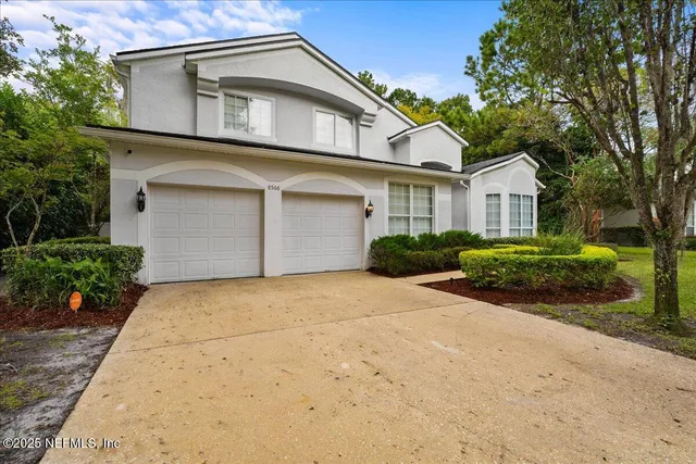 a front view of a house with a garden and trees