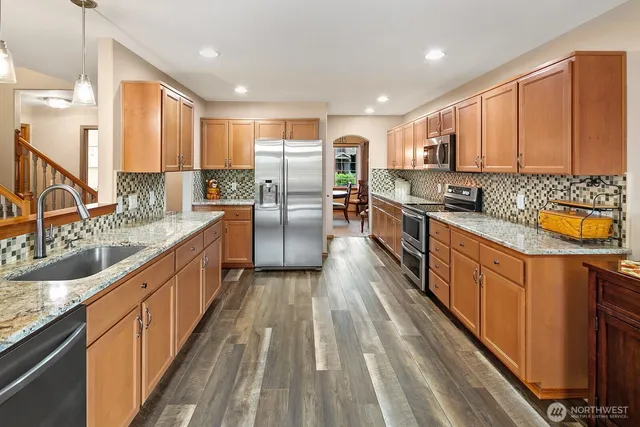 a large kitchen with stainless steel appliances granite countertop sink stove and large window
