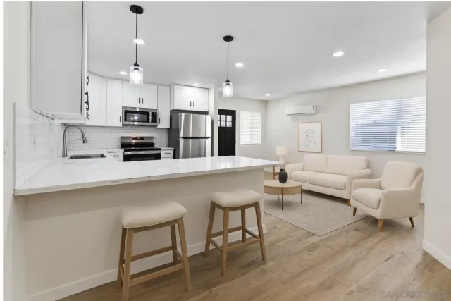 a kitchen with stainless steel appliances kitchen island granite countertop a refrigerator a stove a sink and white cabinets with wooden floor