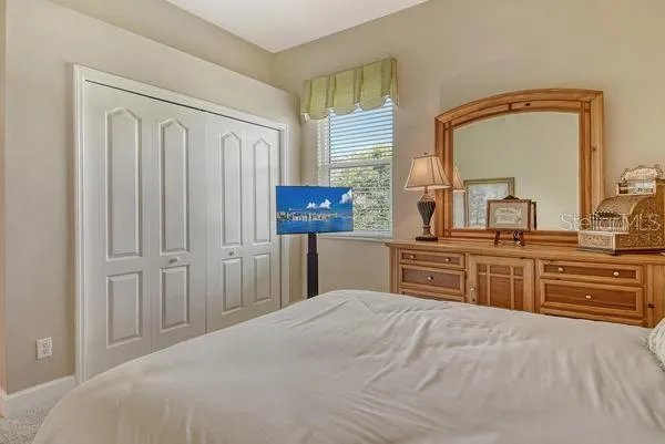 a bedroom with a bed and a mirror on dresser