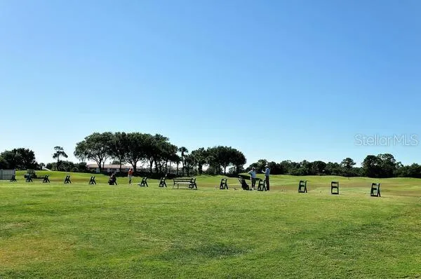 a green field with lots of trees in the background