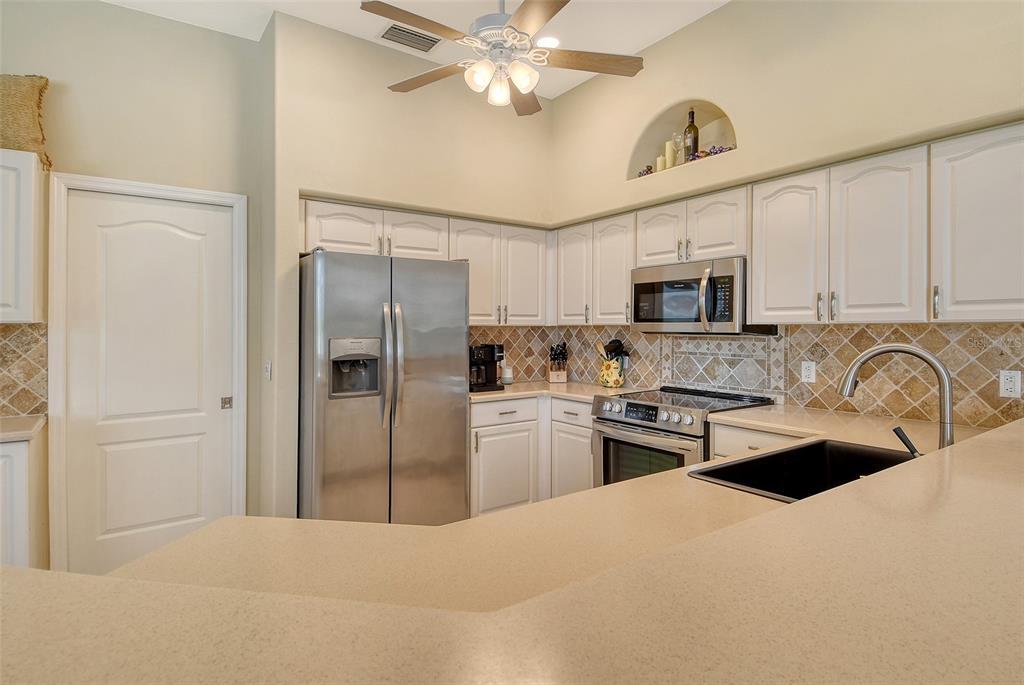 9477 Cedar Ridge Lane Sarasota, FL 34238 - Photo 8 of 51 a kitchen with a refrigerator a sink stainless steel appliances and cabinets